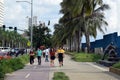 People with masks walking on bay walk to view the artificially face lifted beach coast line dumped with white dolomite sand