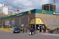 People in medical masks and cars near McDonalds fast food restaurant