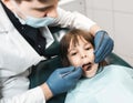 People, medicine, stomatology, technology and health care concept. Male dentist working with little girl in clinic.