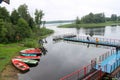 People, men are fishing from the pontoon, apron, bridge on the lake with ducks and boats on the shore at the recreation Royalty Free Stock Photo