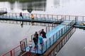 People, men are fishing from the pontoon, apron, bridge on the lake with ducks at the recreation center, sanatoria in the fall