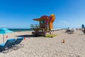 People on Miami beach on beautiful sunny day. Sand beach, tourists and yellow lifeguard tower on blue Atlantic ocean. Royalty Free Stock Photo