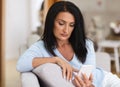 Focused mature woman using smartphone at home