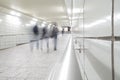 People in motion blur walking down bright white tiled tunnel walkway to subways transit Royalty Free Stock Photo