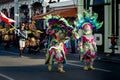 People in motley carnival elephant costumes pass by city street at dominican parade