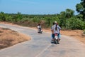 People on motorbikes on a rural asphalt road near Chaung Thar, Irrawaddy, Myanmar