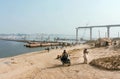 People and motorcyclists hurry on road past the pontoon bridge across the wide river Ganga Royalty Free Stock Photo