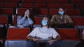 People in movie theater watch scary movie. Media. Watching movies in medical masks during coronavirus pandemic. People Royalty Free Stock Photo