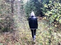 People, mushroom pickers in warm clothes walk in a hike through the autumn forest with trees in the nature along the grass