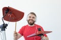 People, music and hobby concept - Tough man in red t-shirt and black sneakers playing electronic drum kit