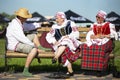 People in national Slavic clothes are sitting on the bench. Belarusians or ukran man and women.