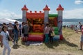 People are near an inflatable children`s trampoline in the form of a castle during the festival Karatag on the shore of Lake Royalty Free Stock Photo
