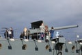 People near a ship`s gun on a cloudy sky background