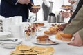 People near table with different delicious snacks during coffee break, closeup