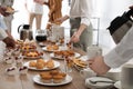 People near table with different delicious snacks during coffee break, closeup