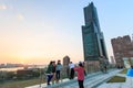 People next to the Tuntex Sky Tower watching the Sunset .