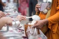 people offer rice to buddhist monk alms-bowl