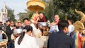 people offering food and items to a buddhist monk and being blessed in temple