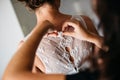 People, one wearing an ornate wedding dress and the other person helping to button it