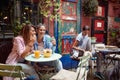 People in outdoor cafe. One female friend showing to another something on her cell phone in outdoor cafe Royalty Free Stock Photo