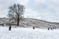 People outdoor having fun in the snow skiing and sledding.