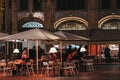 People at outdoor tables of a cafe in Seville, Spain, at night, selective focus