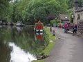 people outside the stubbings wharf pub on the rochdale canal in hebden bridge with barges and houseboats moored along the bank