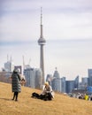People outside walking a dog and enjoying the lake shore at Trillium Park with the CN Tower in the background