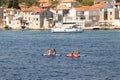 People paddling while sitting on paddleboards and stone houses by the dock behind them, in Prvic, Croatia Royalty Free Stock Photo