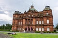 People Palace in Glasgow Green park which is used as a museum with people relaxing on a lwan