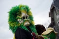 People parading in the street with mask and green wig during the carnival