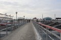 People passengers walk on a pedestrian bridge to the railway station for electric trains