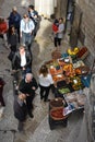 People passing by a street stall full of fruit and vegetables in Bari, Italy
