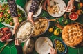 People passing Turkish foods over celebration dinner table, top view