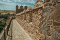 People on pathway over stone thick wall encircling Avila