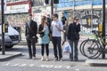 People at the pedestrian crossing are waiting for the traffic light to switch to red