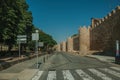 People on pedestrian promenade beside large city wall at Avila