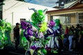 People in pied green demon costumes walk by city street at dominican carnival