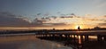 people on the pier at sunset next to the water