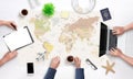 People are planning a holiday trip. Top view of the working tourist agency desk with a large world map in the background Royalty Free Stock Photo