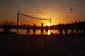 People play volleyball on the beach during the sunset