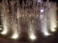 People playing in water fountain jets with lights at night Royalty Free Stock Photo