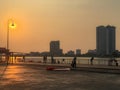 People in plaza with beautiful shades of golden sunset illuminating the lantern