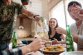 People pouring wine into glass and having dinner with friends