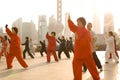 People practicing Tai Chi at sunrise at the riverside of the Huangpu river with Pudong skyline in the background