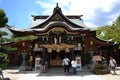 People praying in front of wooden Japanese temple in Fukuoka. Tr