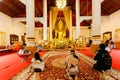 People praying inside big hall of historical temple with golden Buddha statue Royalty Free Stock Photo
