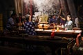 People praying and smoking up incense sticks in a buddistic asian temple. Thien Hau pagoda, Saigon with light rays shining inside