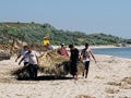 People preparing Tuzla wild beach for the summer season by installing umbrellas