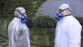 People in protective suits and respirators in the city Park talking Royalty Free Stock Photo